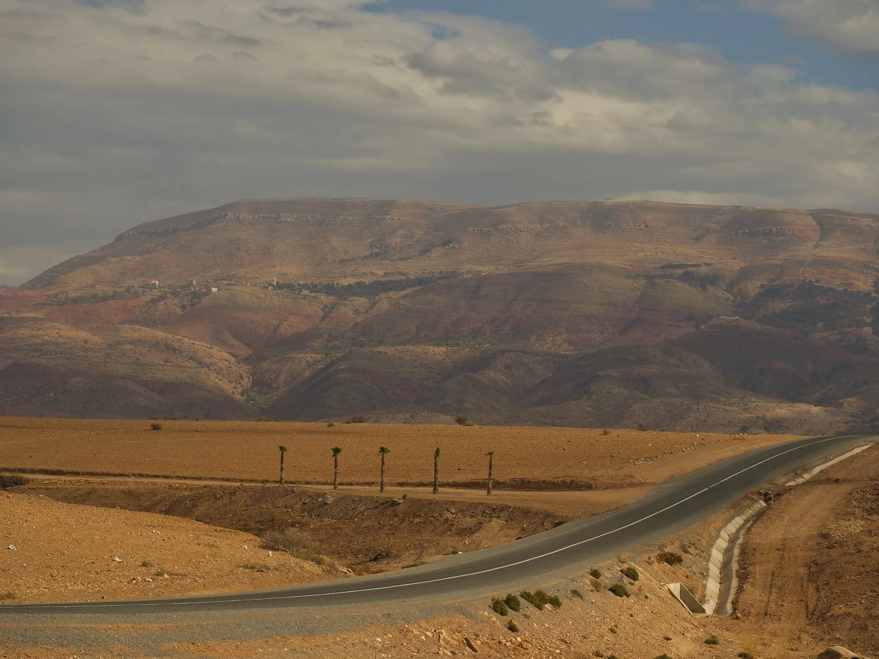 Route dans le paysage pierreux d’Agafay, avec l’Atlas à l’horizon