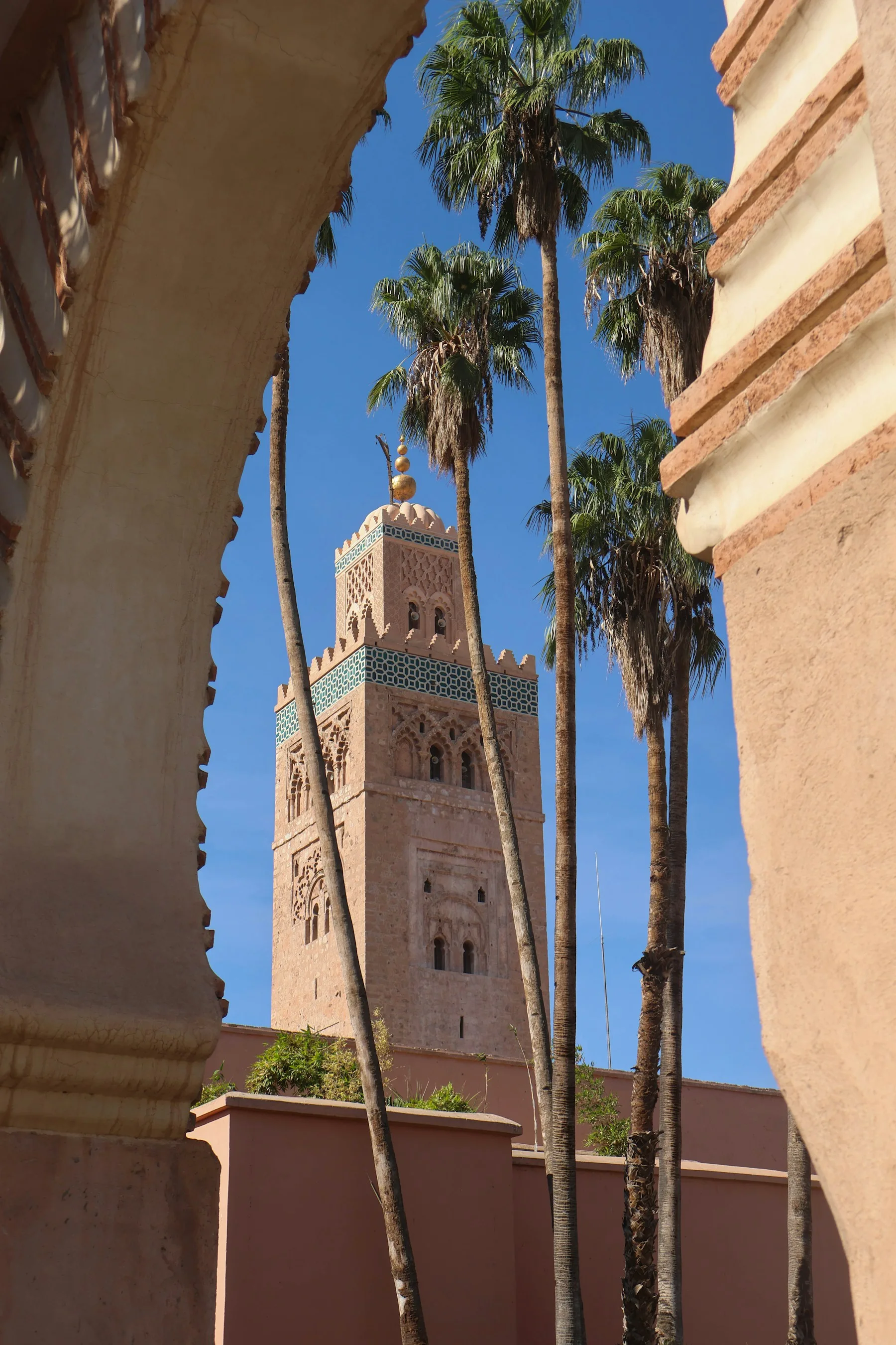 Le minaret de la Koutoubia derrière une arche et des palmiers à Marrakech
