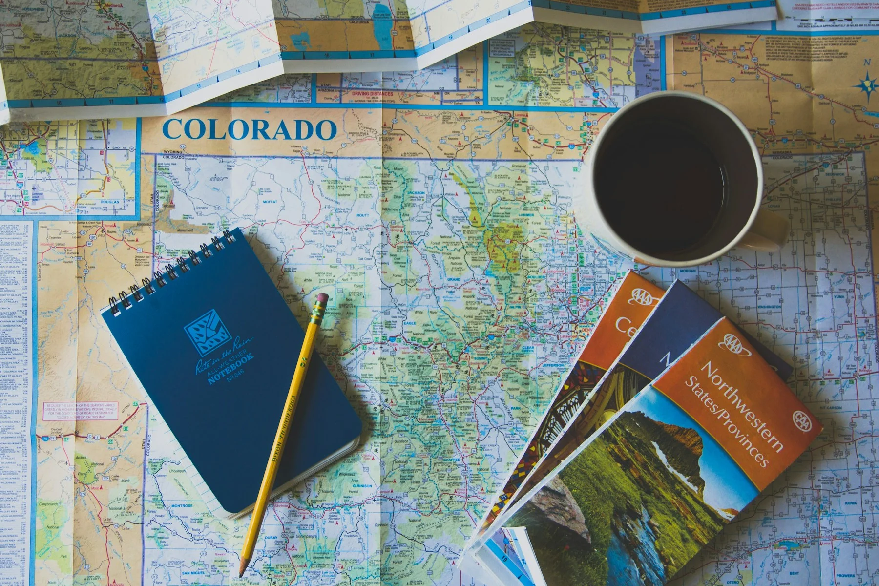 Cartes nord-américaines, carnet bleu, crayon et tasse : illustration de préparation d’un itinéraire.